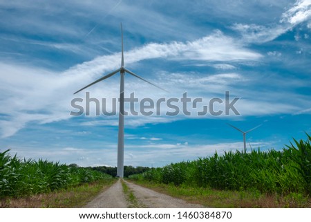 Close view of onshore horizontal axis wind turbine (windmill) in green field, deep blue sky, sunny day. Ontario Canada. Replenishable green renewable alternative energy and natural sources concept.