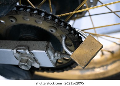 close up view of a padlock installed on a motorcycle chain as an additional anti-theft security system