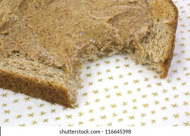 Close View Of A Piece Of Wheat Toast With Almond Butter That Has Been Bitten On A Paper Napkin.