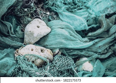 Close up view pile of green nylon multi colorful bright fish nets with pieces of white corals and old ropes in fishing village. Still life background pattern. Hobby fishing concept. Copy space