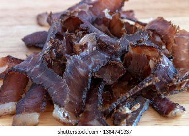 A close up view of a pile of south african biltong on a wood cutting board