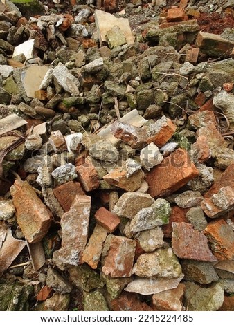 Close up view of piles of red brick rubble and cement stone from collapsed walls