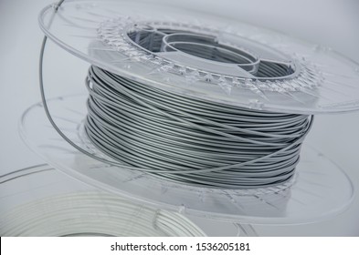 Close Up View Of Plastic For 3D Printing. Silver Plastic Filament, Gray ABS/PLA Coil For 3d Printer Isolated On White Background.  Plastic For Three-dimensional Object Creation. Additive Manufacturing