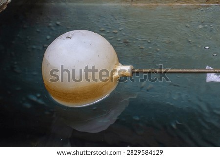 Close up view of a plastic spherical float ball floating on clean water surface inside a storage tank