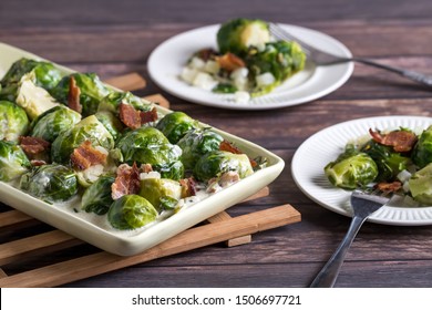 Close up view of a platter of cooked brussel sprouts and two servings on a wooden table.