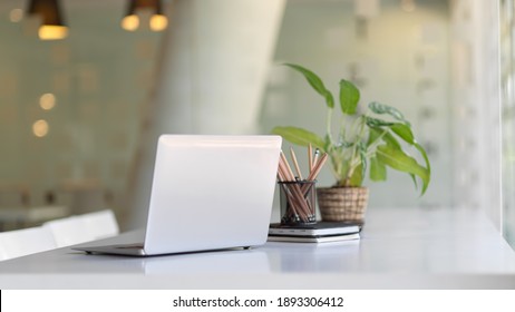 Close up view of portable workspace with laptop, stationery and plant pot o the table in co-working space - Shutterstock ID 1893306412