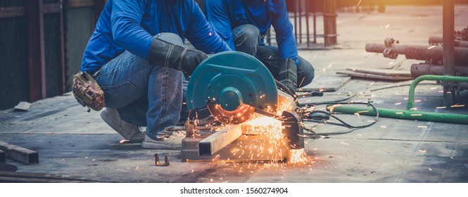 Close up view of professional focused two worker man in uniform working on the metal pipe sculpture with an electric grinder while sparks flying in the industrial outdoor site constuction. - Powered by Shutterstock