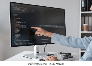 Close up view of programmer pointing to desktop computer with developing programming code, trying to solve the problem.