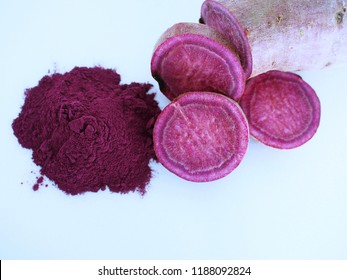 Close Up View Of Purple Sweet Potato Powder With Raw Purple Sweet Potato, Cut In Pieces, Isolated