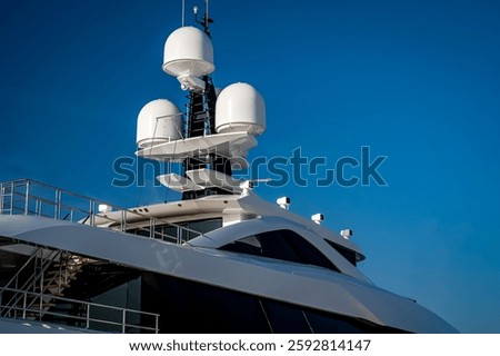 Close up view of the radar navigation system and communication mast on a white modern super mega yacht with blue sky in the background