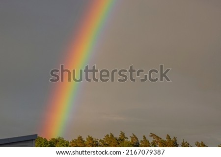 Close up view of rainbow in cloudy evening summer sky. Sweden.