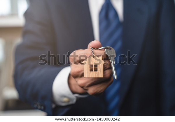 Close up view realtor broker holding home keychain\
in his hand.