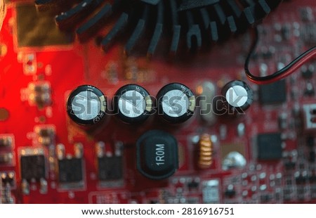 Close up view of red electronic circuit board with capacitors and cooling elements, showing modern technology, precision engineering and digital hardware details.