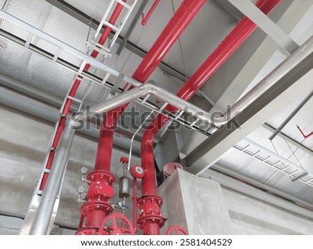 A close up view of a red fire hydrant pipe system, showcasing its industrial design and essential safety features. Highlights the sturdy construction, valves, and connections used for firefighting