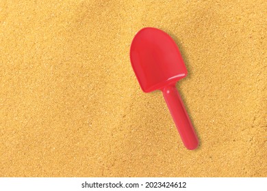 Close Up View Red Sand Shovel Isolated On Sand Beach. Added Copy Space For Text.