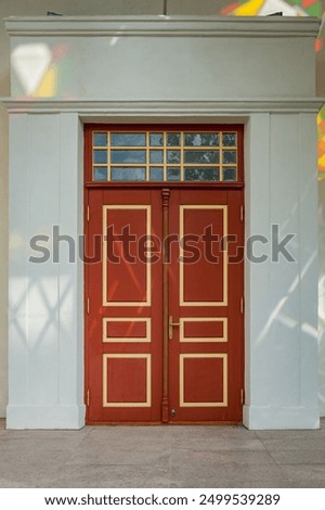 A close up view of a red-brown door with glints of stained glass. Retro entranceway.