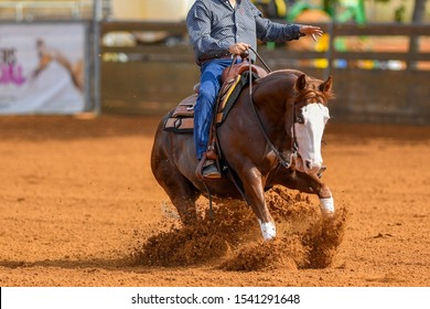 A close up view of a rider sliding the horse in the sand