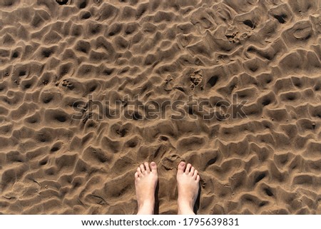 a close up view of the ripples in the sand from the low tide with someones feet 
