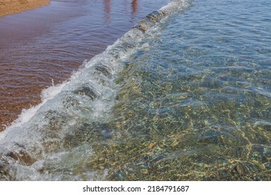 Close up view of rolling waves on sandy beach of sea.