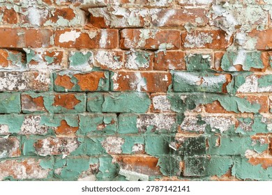 Close up view of rustic brick wall with peeling green paint.