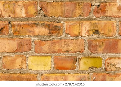 Close up view of rustic brick wall with peeling yellow paint.
