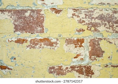 Close up view of rustic brick wall with peeling yellow paint.