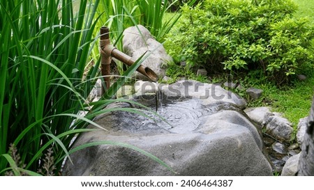 Close view of a rustic zen bamboo water fountain in a green garden