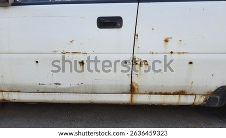 Close up view of a rusty white car door, showcasing visible corrosion and damage, emphasizing the impact of time and neglect on the vehicle weathered exterior