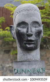 Close Up View Of Saint Canice Bust In Kilkenny Ireland, Also Called St Cainnech. Grey Sculpted Face Of The Saint With The Name. Green Leaves Of Trees In Background. Picture Taken On 9th August 2016.