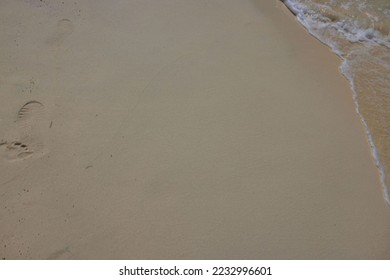 Close up view of sandy beach surface with footprint and incoming waves.  Beautiful nature backgrounds concept. 