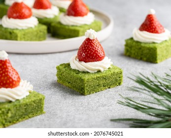 Close Up View Of Santa Hat Shaped Cakes With Cream Cheese And Fresh Strawberry. Green Spinach Biscuit With White Whipped Cream And Red Berry. Christmas And New Year Background. Festive Dessert.