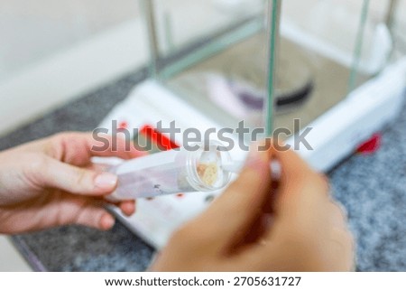 Close up view of a scientist hand using a spoon to fill a plastic test tube labeled potato with mashed raw vegetable pulp for chemical analysis in the modern agricultural laboratory indoors