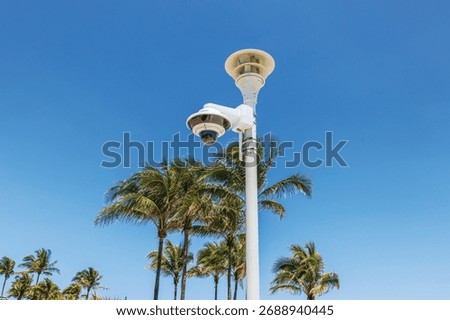 Close up view of security surveillance camera on Ocean Drive with palm trees and clear blue sky on background. Miami Beach. USA.