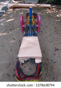 Close Up View Of See Saw Or Jungkat Jungkit Or Teeter Totter Board Up And Down. Illustration Children Toy Play At Garden Park Backyard Isolated On Tree And Sand Background