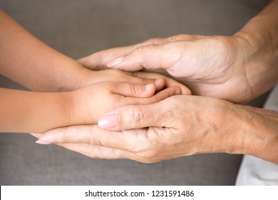 Close Up View Of Senior Grandmother Holding Hands Of Little Kid Granddaughter As Concept Of Elderly Granny Protecting Child, Different Old And Baby Generations, Giving Love Care Support To Grandchild