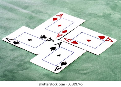 Close up view of a set of four aces spread on a green cloth table.