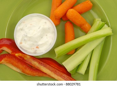 A Close View Of Several Pieces Of Red Pepper, Baby Carrots, Celery And Ranch Dressing On A Green Plate.