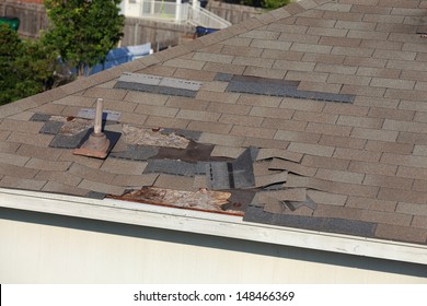 A close up view of shingles being blown off a roof and other roof damage