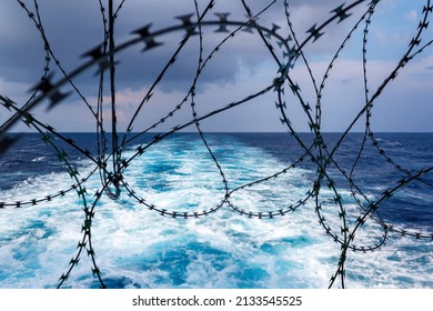 Close up view of ship's stern fortified with razor wire. Anti piracy protection. HRA, High Risk Areas. Illegal boarding. Ship's wake in background. Selective focus.