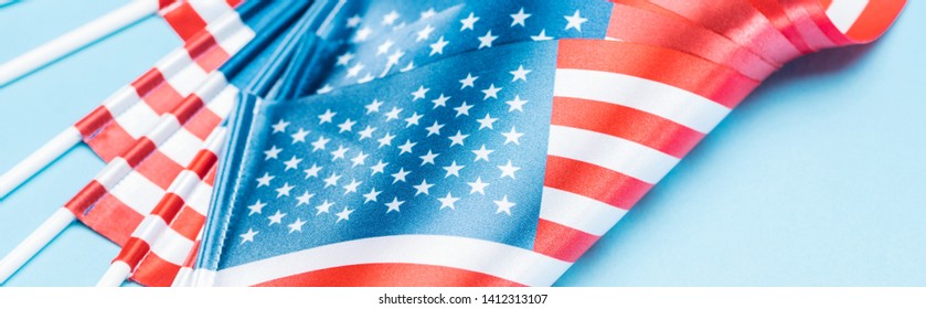 close up view of silk usa flags on sticks on blue background, panoramic shot  - Shutterstock ID 1412313107