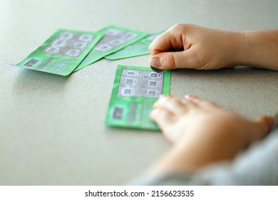 Close up view of silver coin in hand of gambler scratching fake lottery card. Lottery gambling concept, scratching cards lottery type - Powered by Shutterstock