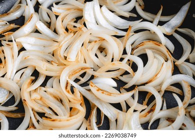 Close Up View of Sliced Onions Browned in a Skillet: Slices of sweet onion cooked in olive oil browning in a frypan - Shutterstock ID 2269038749