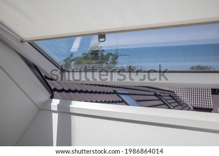Close up view at slightly opened white Tilt Window Skylights  at attic and defocused of the roof.