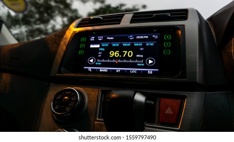 The close up view of the smart multimedia touchscreen radio panel in the car with street light flare during the rain. Car system control using panel button screen interface modern design.