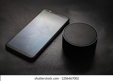 Close Up View Of A Smart Phone And Wireless Speaker On Leather Surface