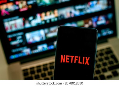 Close up view of a smartphone and Netflix ​logo on display. Computer on background. New technology, series, network, film, cinema, comedy, entertainment concept. Milan, Italy - October 2021