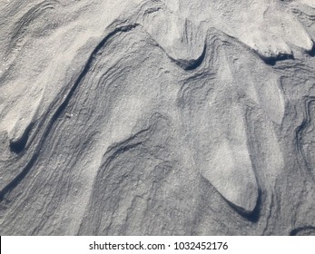 Close up view of snow carpet surface with wave pattern formed by strong wind, natural white textured background