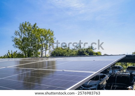 Close up view of solar panels installed on a carport with trees and parked cars under a clear blue sky. Showcasing renewable energy, sustainability, and efficient solar power systems for clean energy.