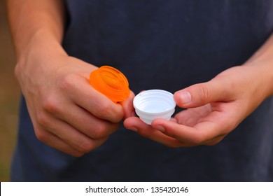 Close Up View Of Someone Opening Up An Orange Prescription Bottle With A White Top