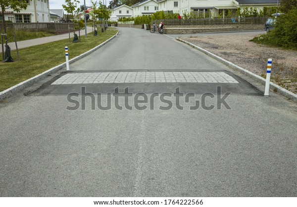 Close\
up view of speed bump on village street road. Landscape view\
background. Europe. Sweden. Uppsala. 06.06.2020.\
\
